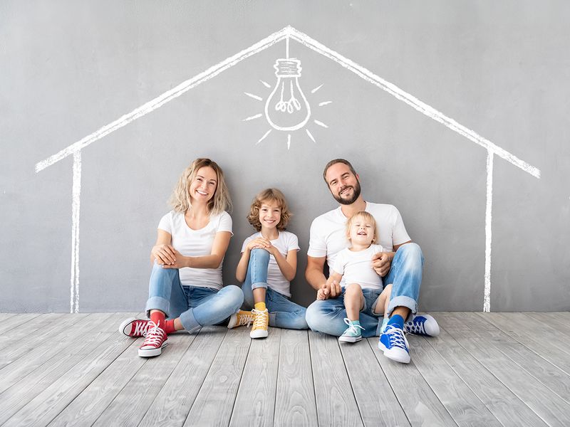 Une famille devant une maison dessinée à la craie, symbole d'un projet d'auto-construction
